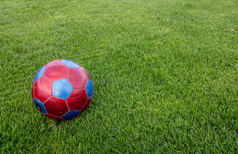 Red soccer ball in the middle of a indoor soccer field